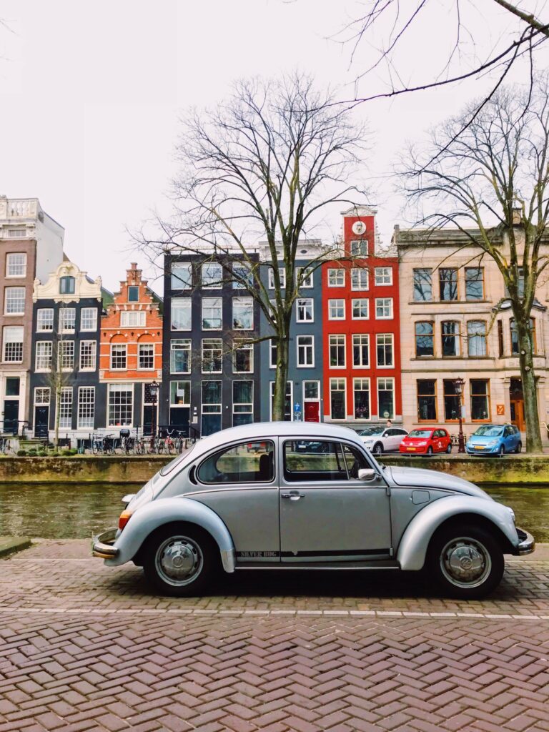 Coccinelle vintage argentée devant les maisons colorées d’Amsterdam