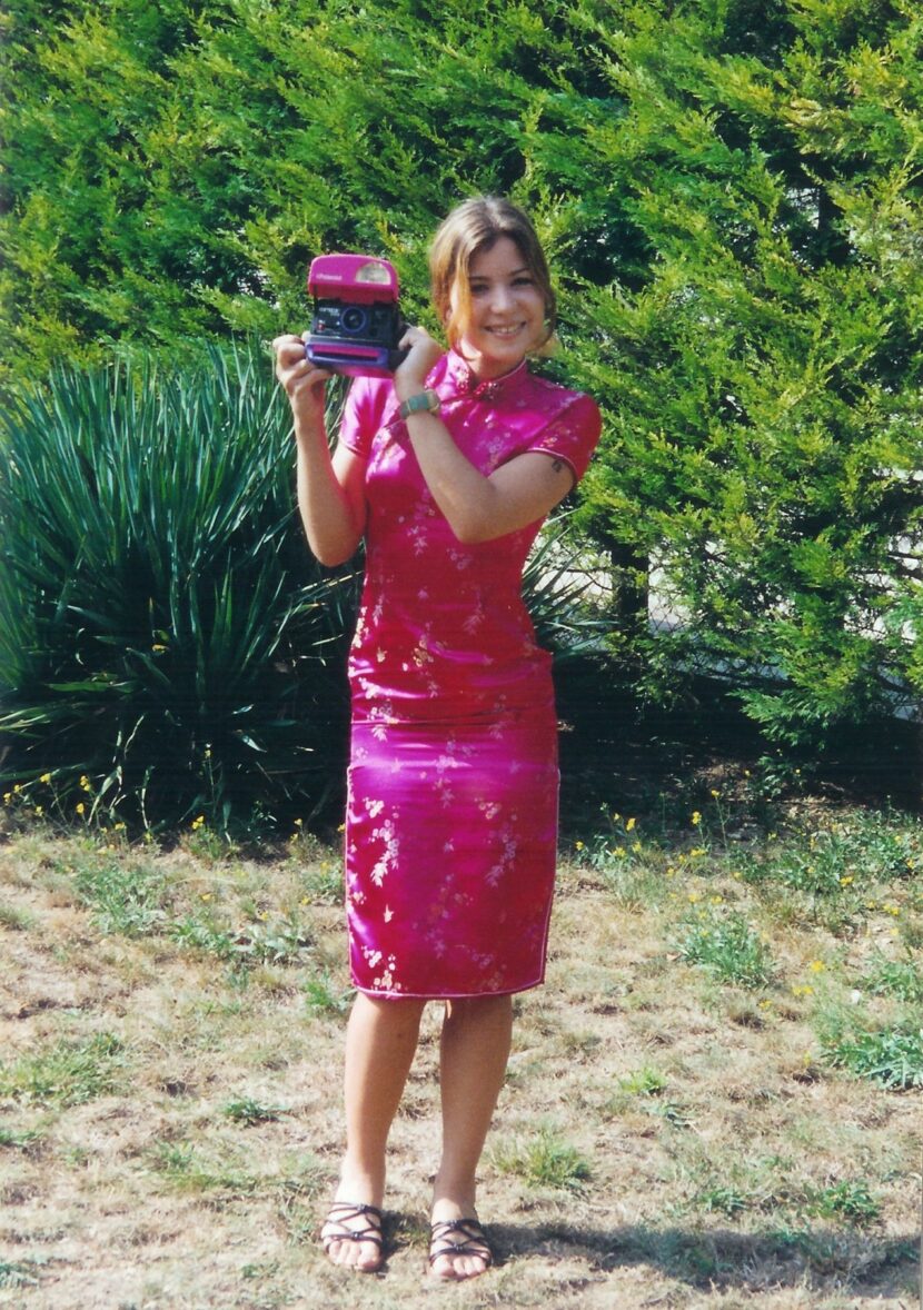 Betty Autier en 1999 version Geri, robe chinoise rose et appareil photo Polaroid
