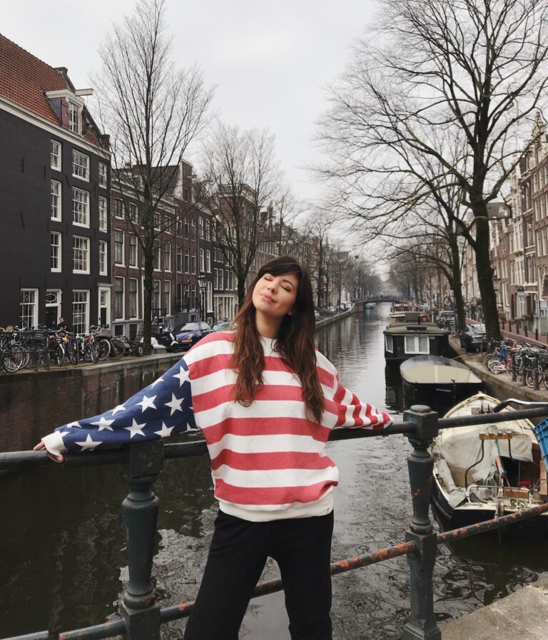 Betty Autier en pull drapeau américain sur un pont au-dessus d’un canal d’Amsterdam