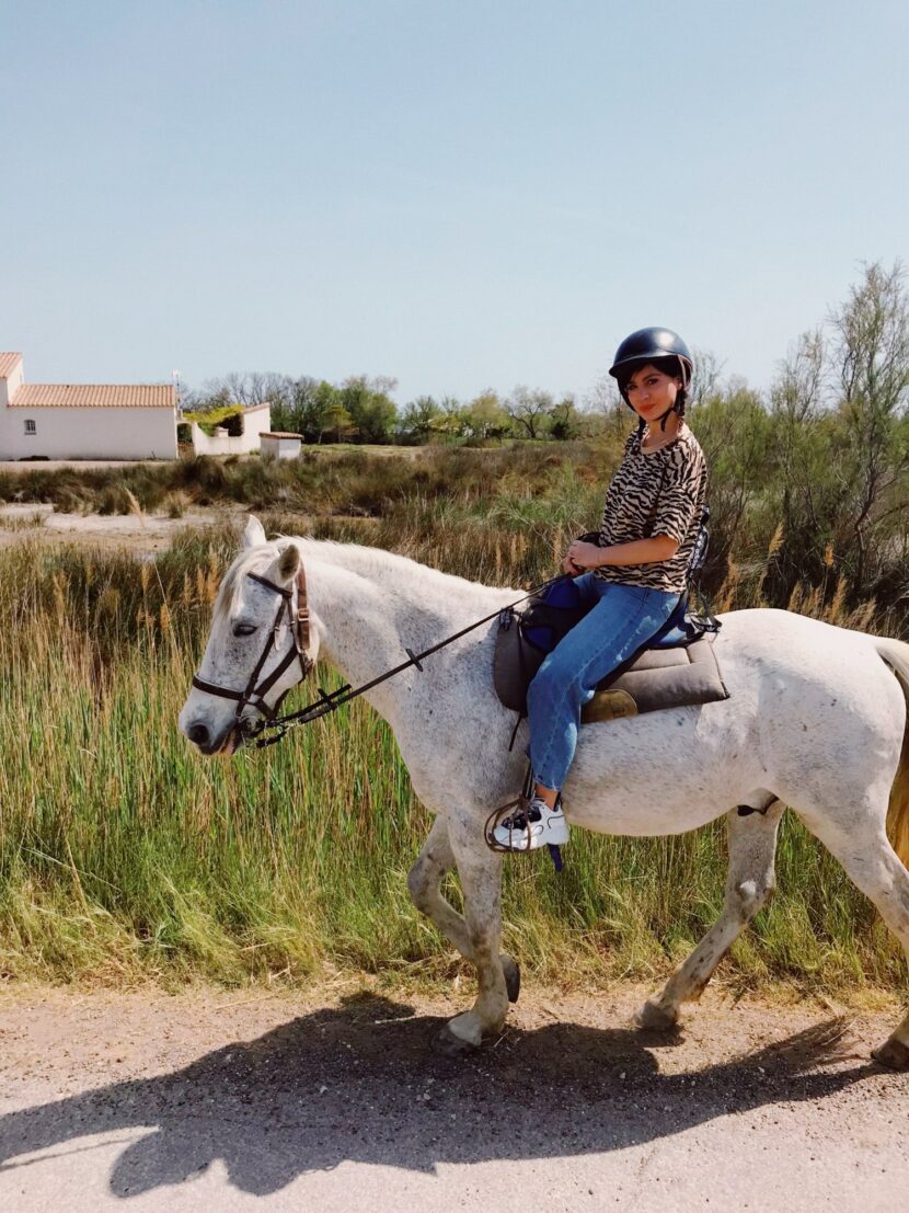 Betty Autier en tee-shirt zèbre et jean lors d’une balade à cheval en Camargue