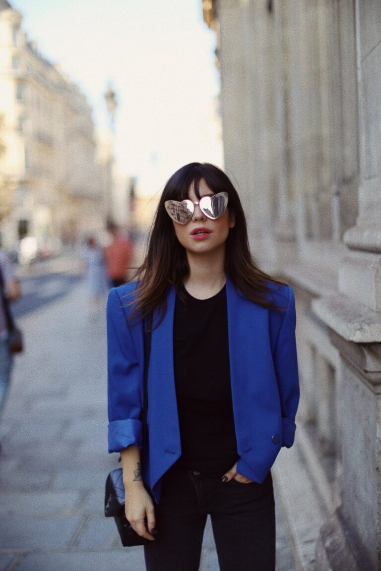 Betty Autier en blazer bleu et lunettes cœur Saint Laurent