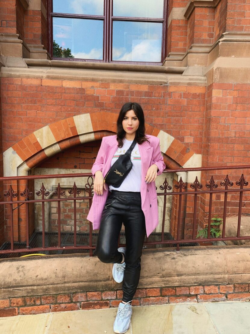 Betty Autier en blazer rose à rayures, tee-shirt Gucci, pantalon en cuir et Yeezy devant la gare de St Pancras à Londres