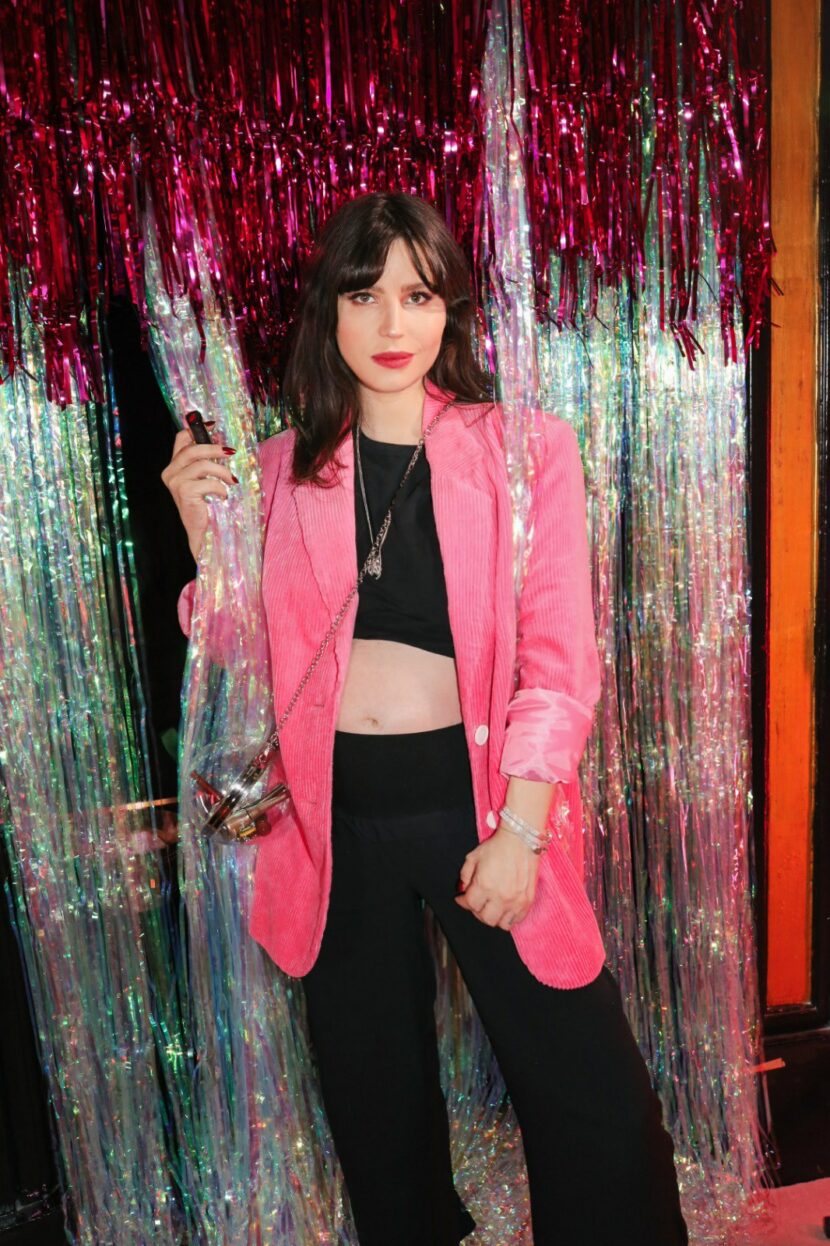 Betty Autier en blazer en velours rose devant le rideau à paillettes