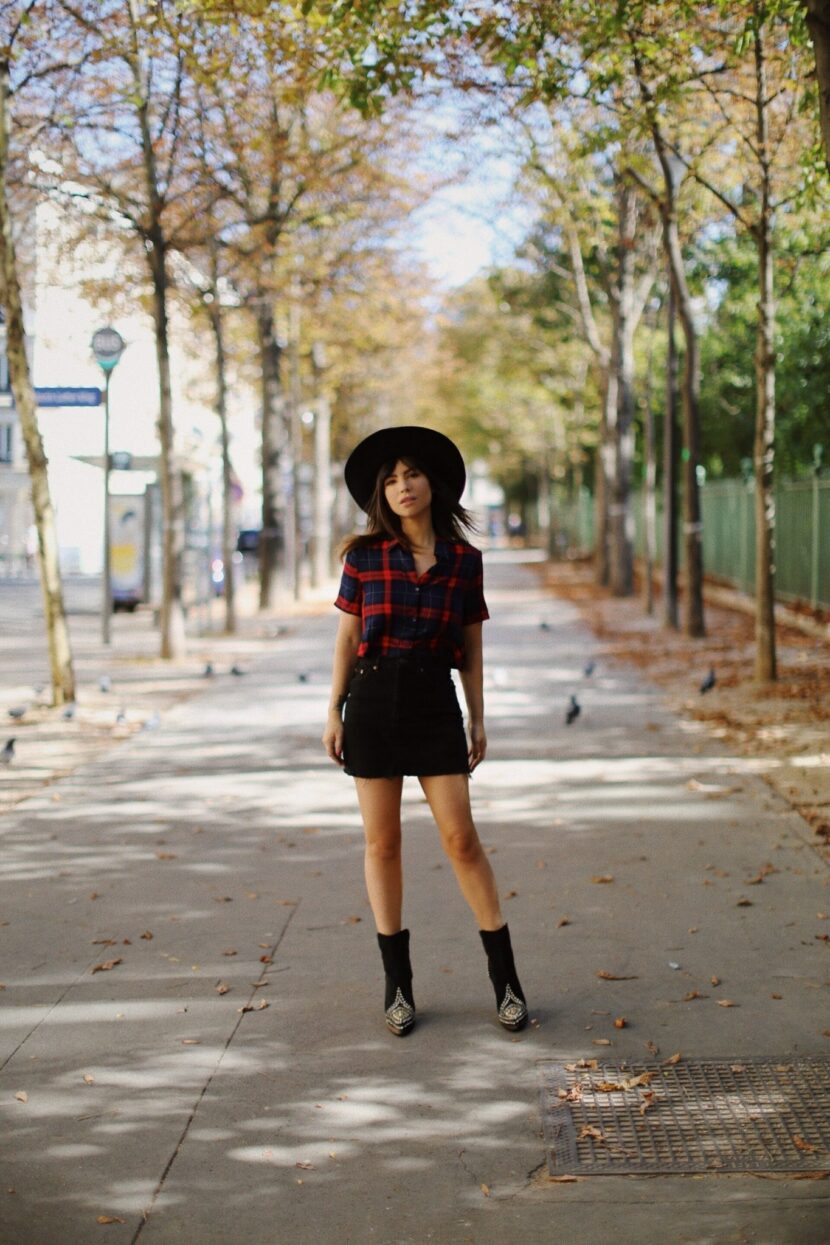 Betty Autier en chemise tartan, jupe en jean noir et chapeau noir à Paris