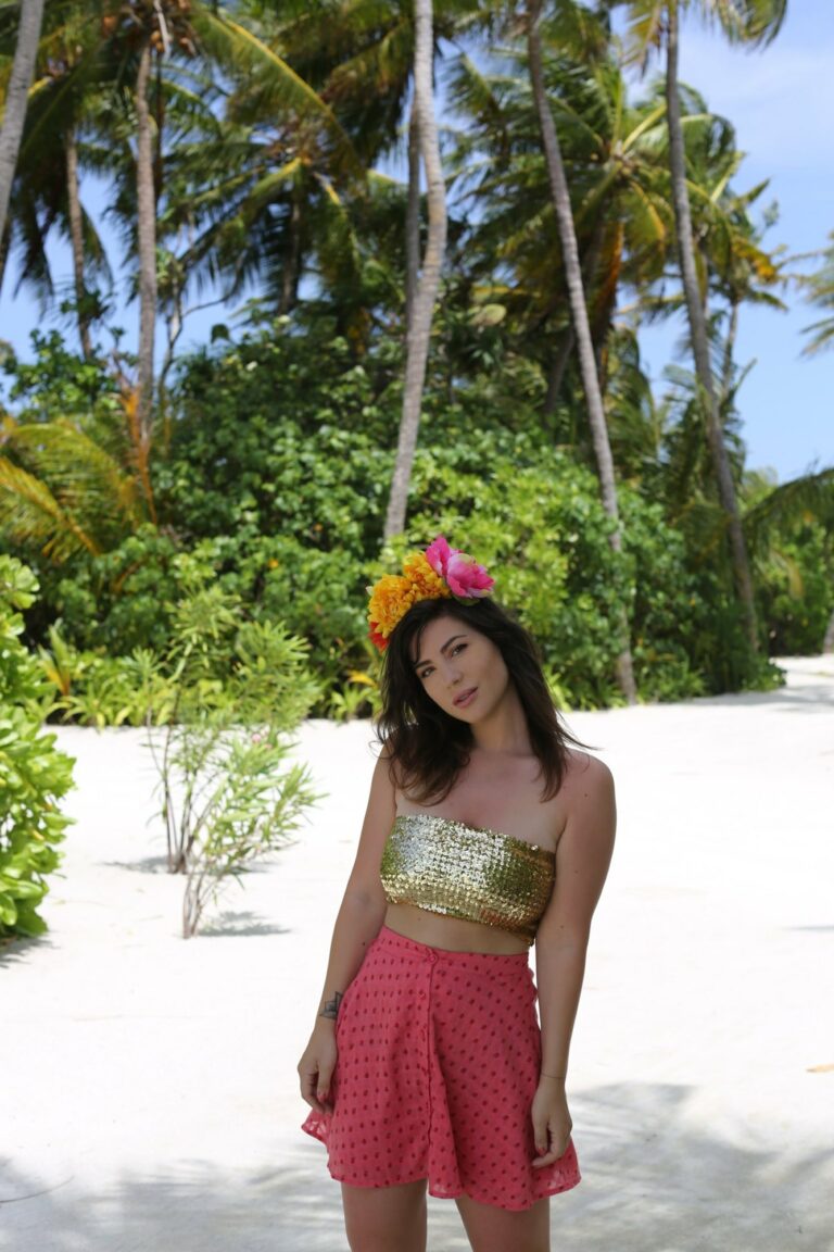Betty Autier en couronne de fleurs, bandeau à sequins doré et jupe rose sur la plage