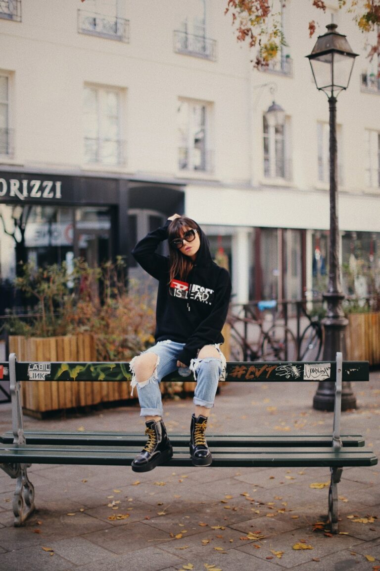 Betty Autier en sweat Diesel is dead et jean destroy assise sur un banc à Paris