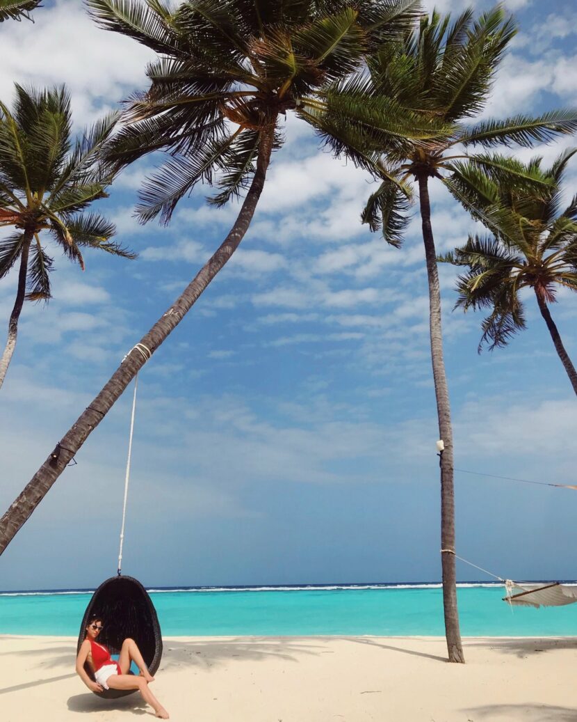 Betty Autier dans un fauteuil œuf suspendu à un palmier, plage du One&Only Reethi Rah