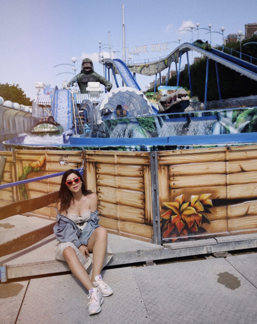 Betty Autier assise devant le Flume Ride de la fête foraine des Tuileries