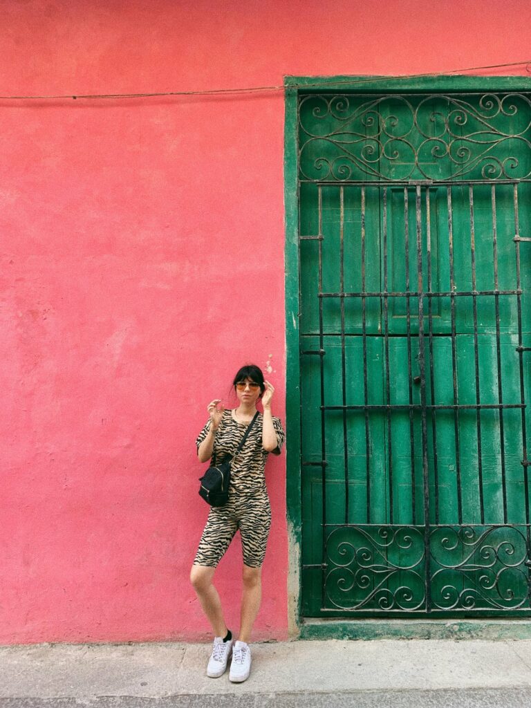 Betty Autier devant un mur rouge et une porte verte à La Havane