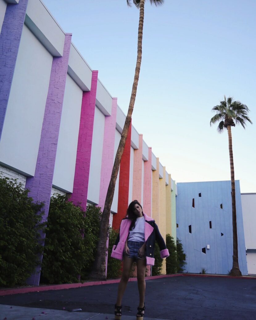 Betty Autier en manteau H&M x Kenzo devant le mur arc-en-ciel du Saguaro