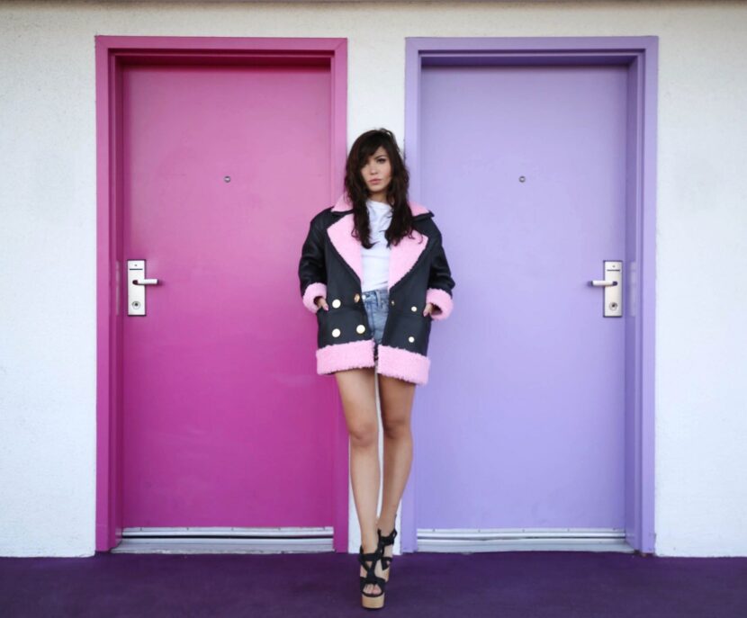 Betty Autier en manteau H&M x Kenzo devant les portes rose et violette du Saguaro à Palm Springs