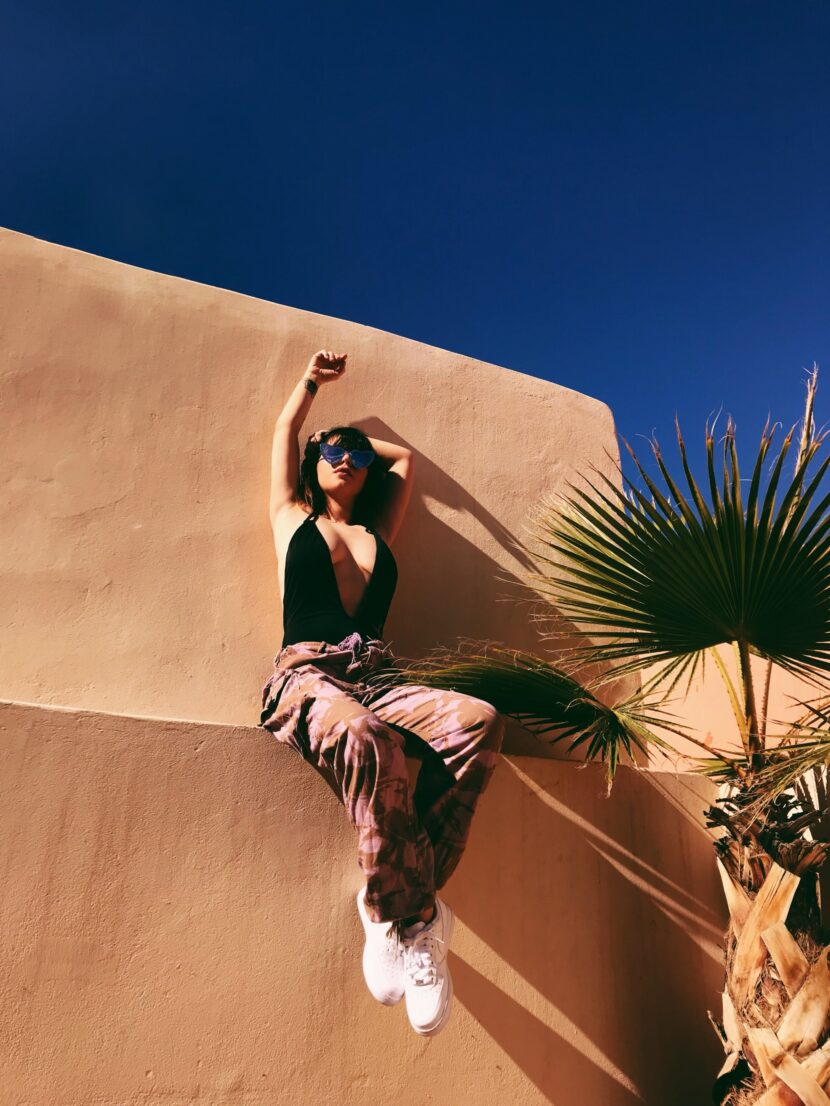 Betty Autier en treillis camo rose assise sur un mur ocre sous le ciel bleu de Marrakech