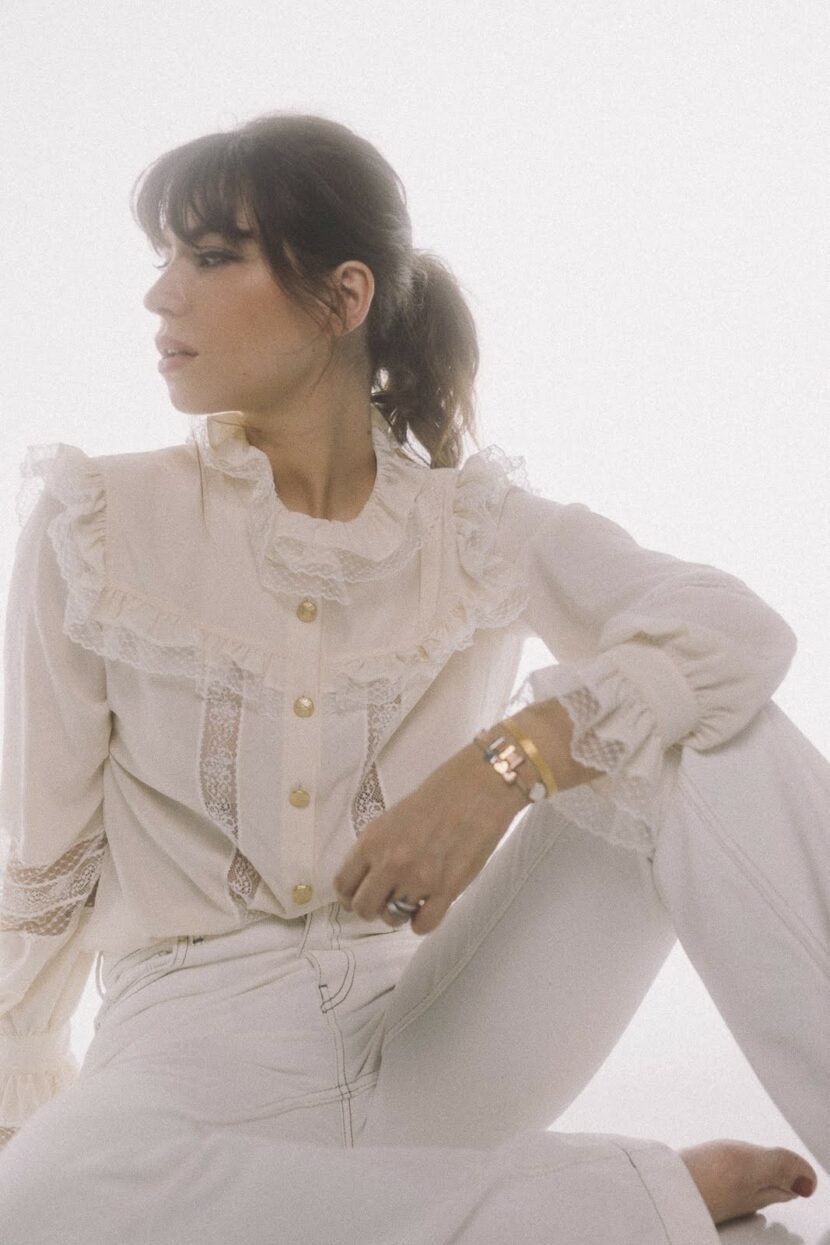 Betty Autier de profil en blouse en dentelle, bracelets or et rose gold