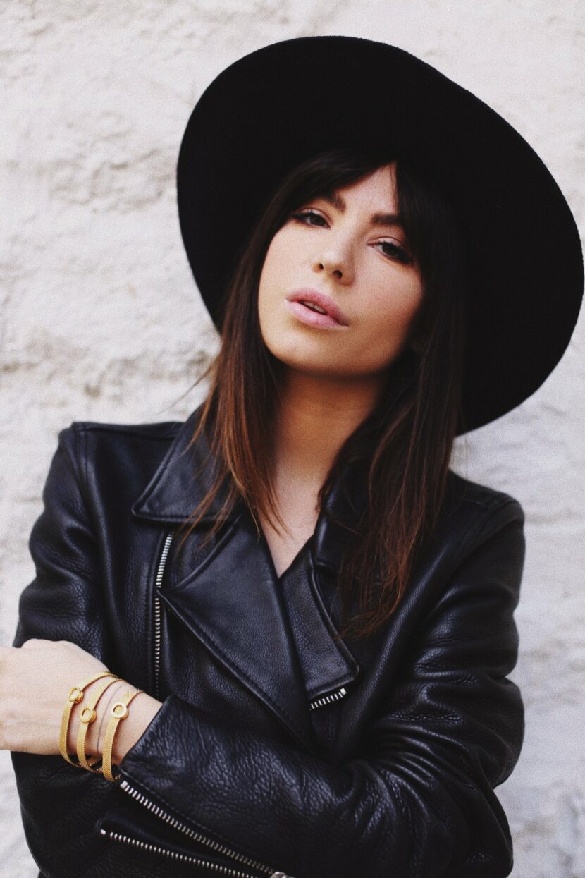 Betty Autier en chapeau noir et perfecto, bracelets Pandora Reflexions dorés