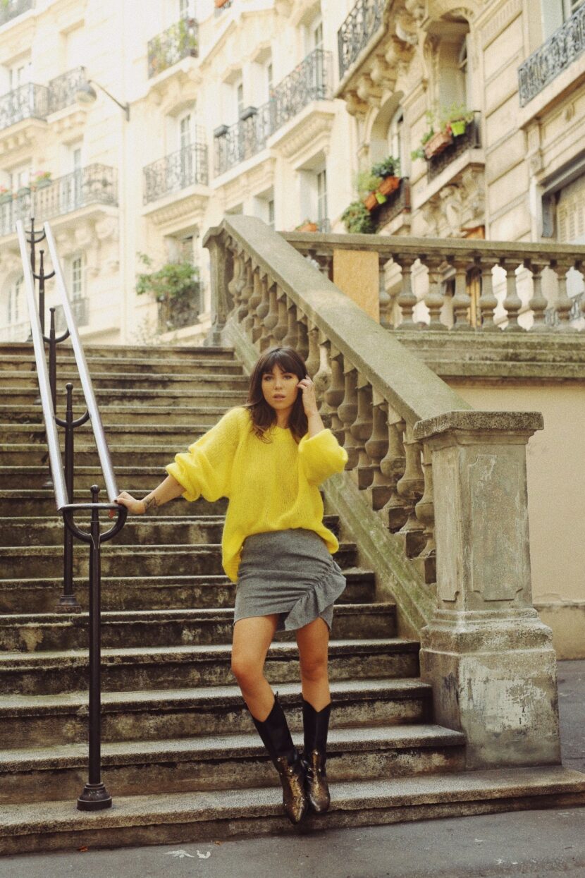 Betty Autier en pull jaune et jupe Iro dans un escalier de Montmartre
