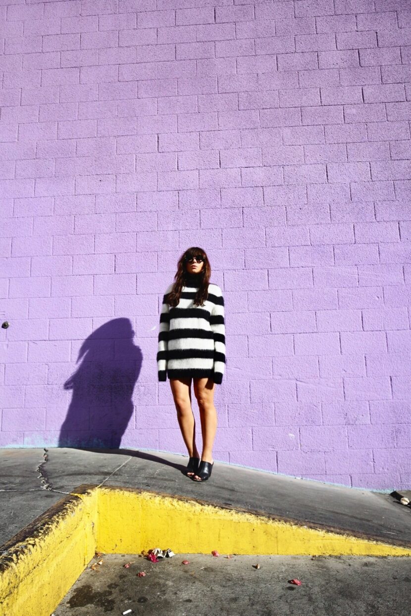 Betty Autier en pull rayé John Galliano devant un mur violet à Los Angeles
