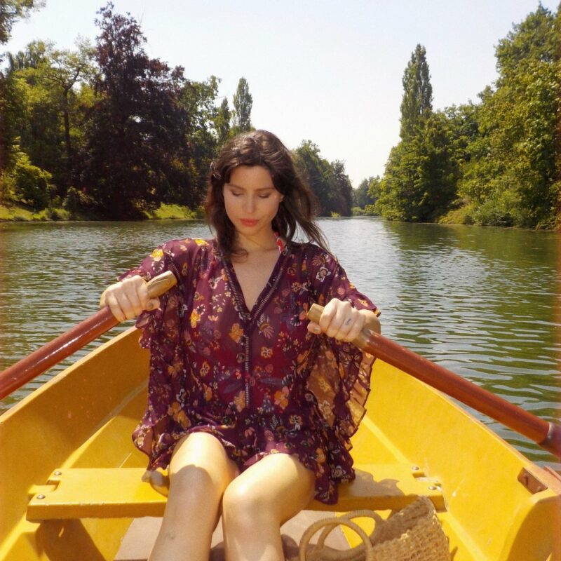 Betty Autier rame dans une barque jaune sur le lac du Bois de Boulogne, panier en paille à ses pieds