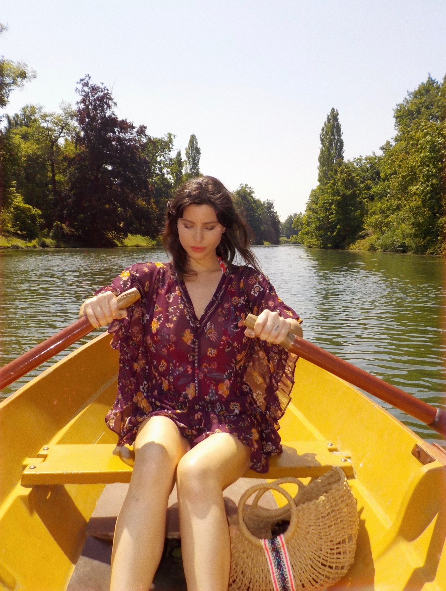Betty Autier rame dans une barque jaune sur le lac du Bois de Boulogne, panier en paille à ses pieds