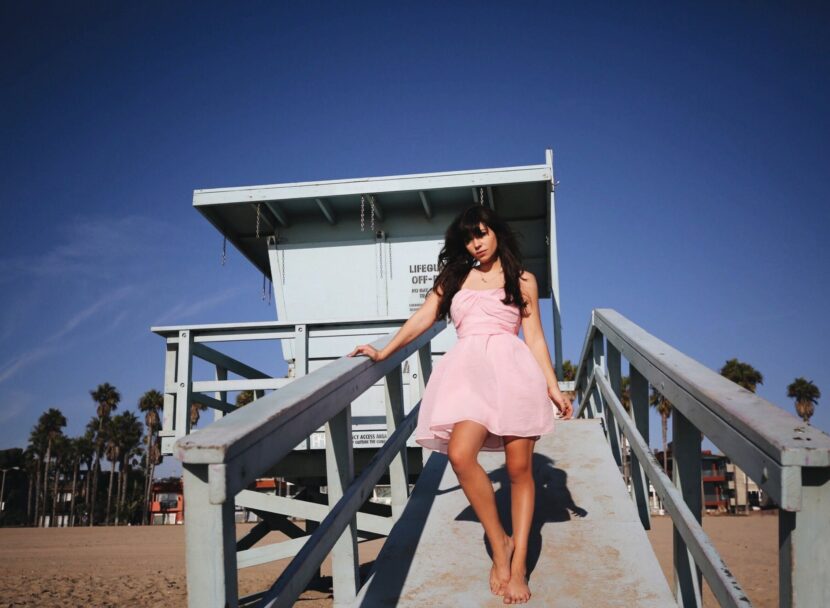 Betty Autier en robe rose Carven sur un poste de sauveteur à Venice Beach