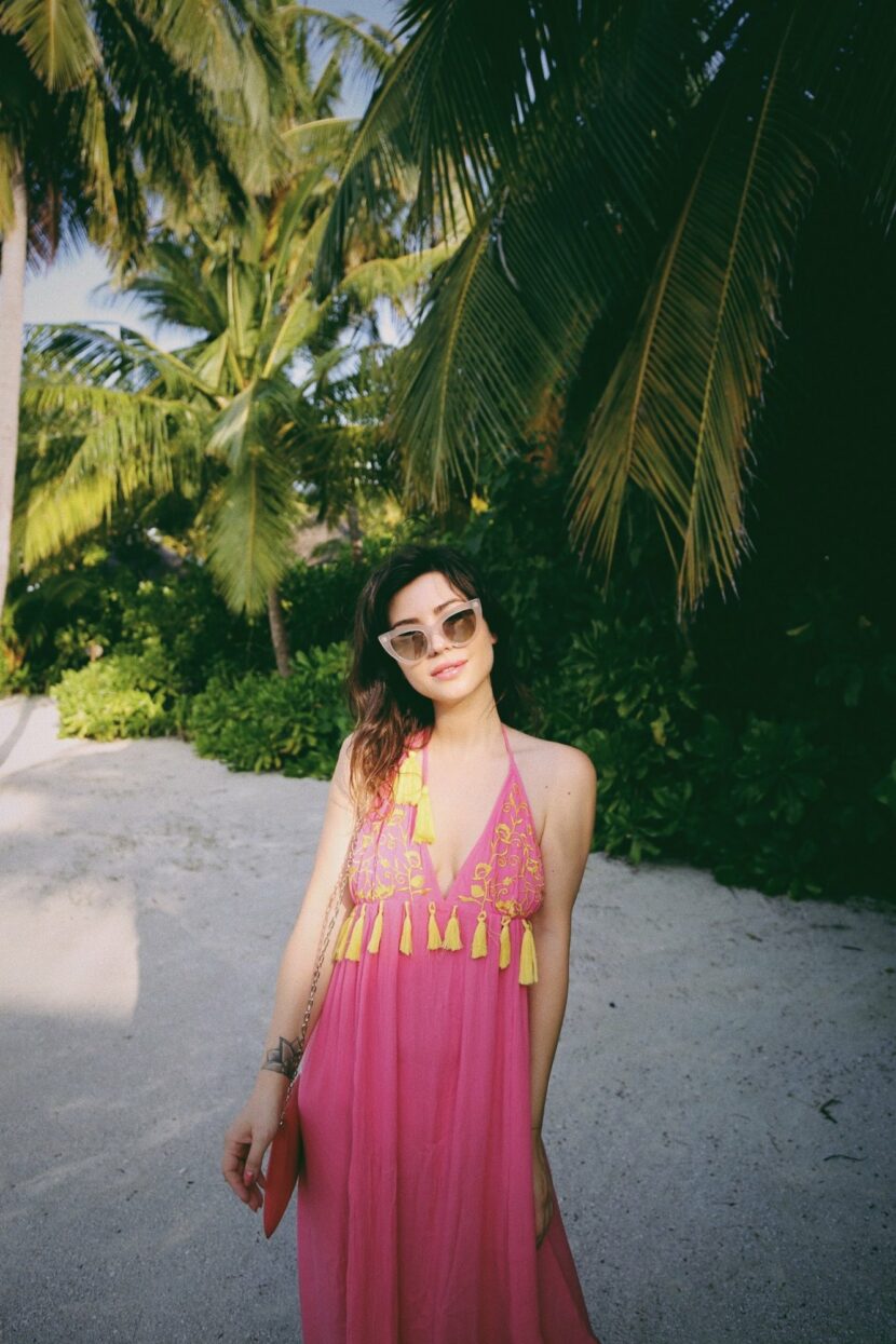 Betty Autier en robe rose à pompons et lunettes œil de chat au One&Only Reethi Rah