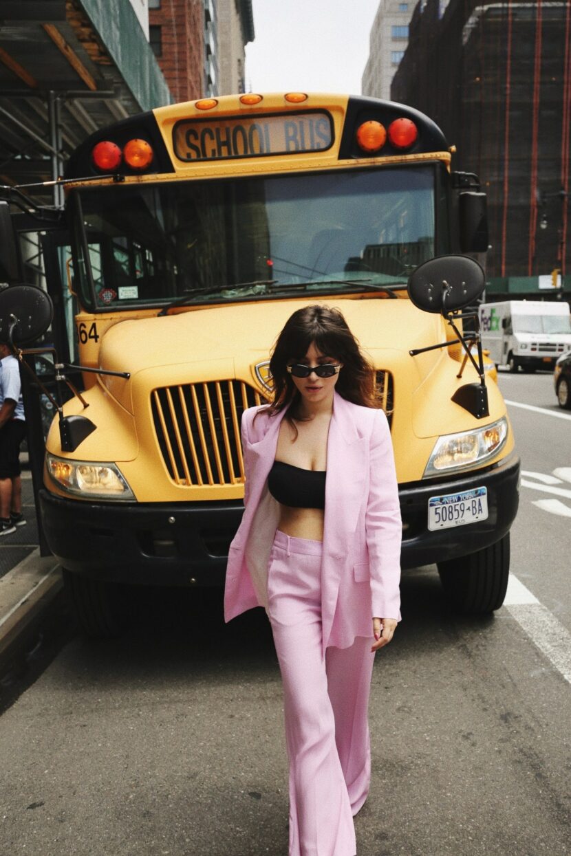 Betty Autier en tailleur rose devant un school bus jaune à New York