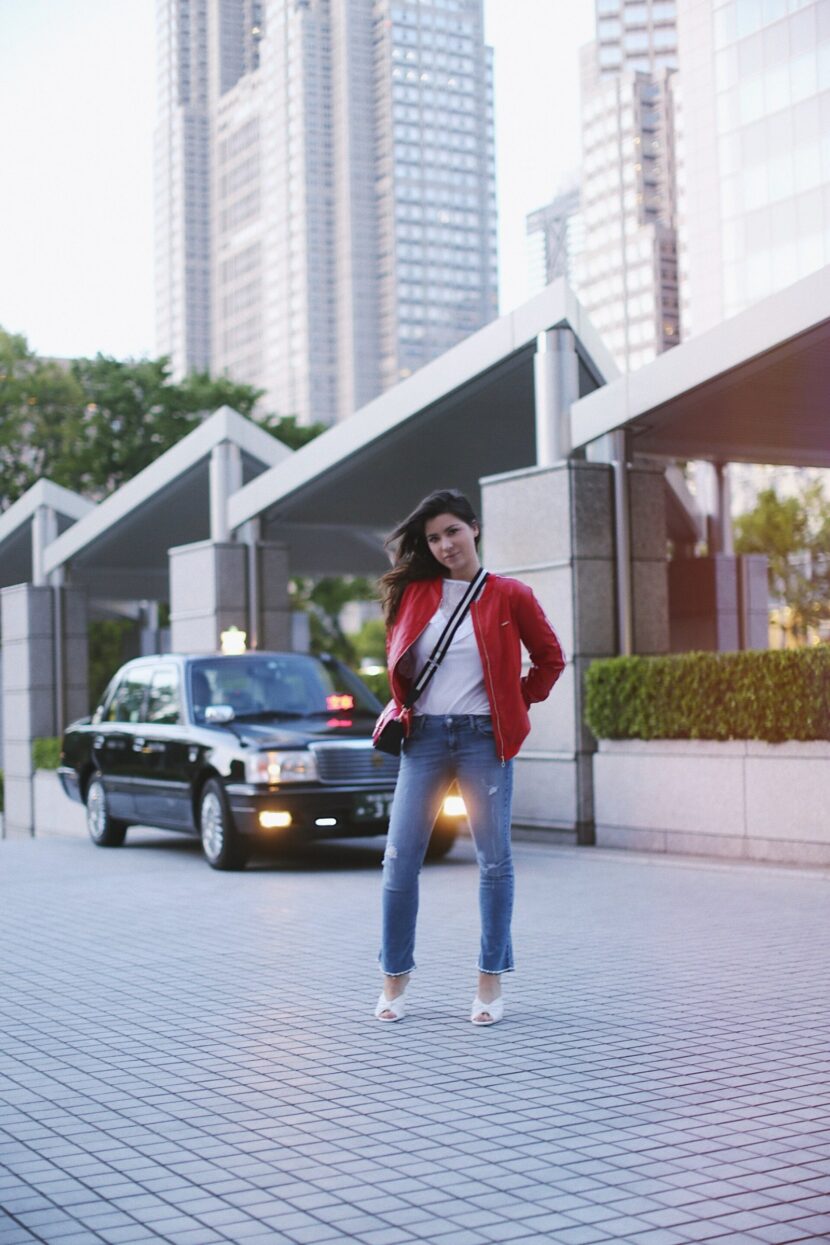 Betty Autier en blouson rouge devant un taxi à Tokyo