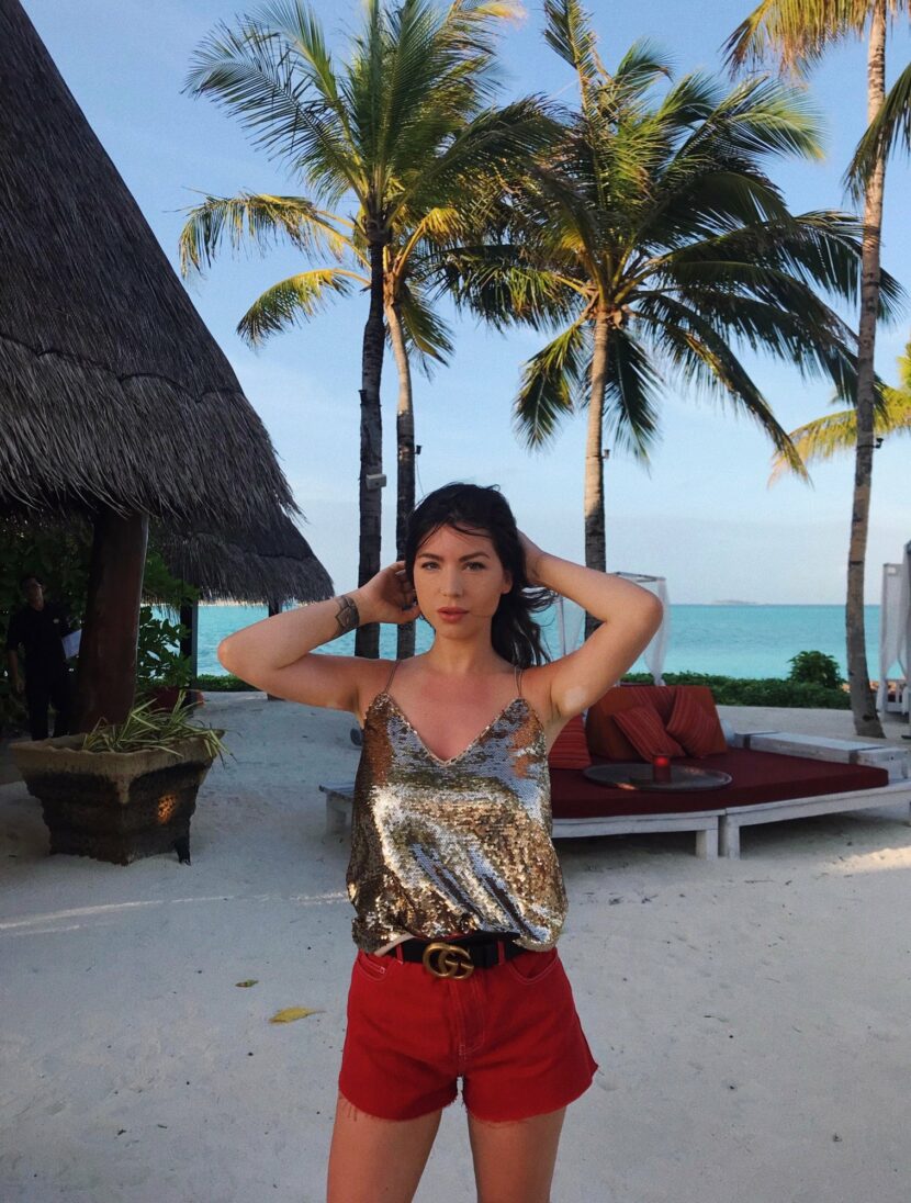 Betty Autier en top à sequins, short rouge en jean et ceinture Gucci au coucher du soleil