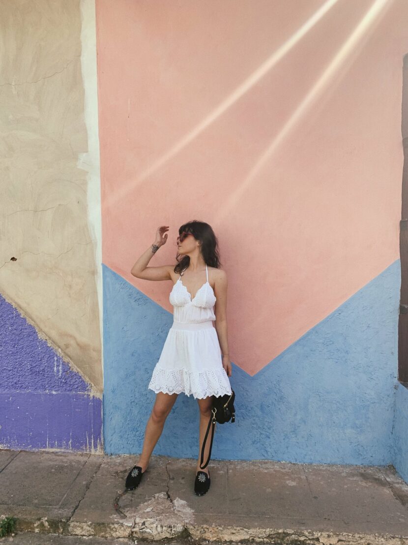 Betty Autier en robe blanche devant un mur rose à Trinidad