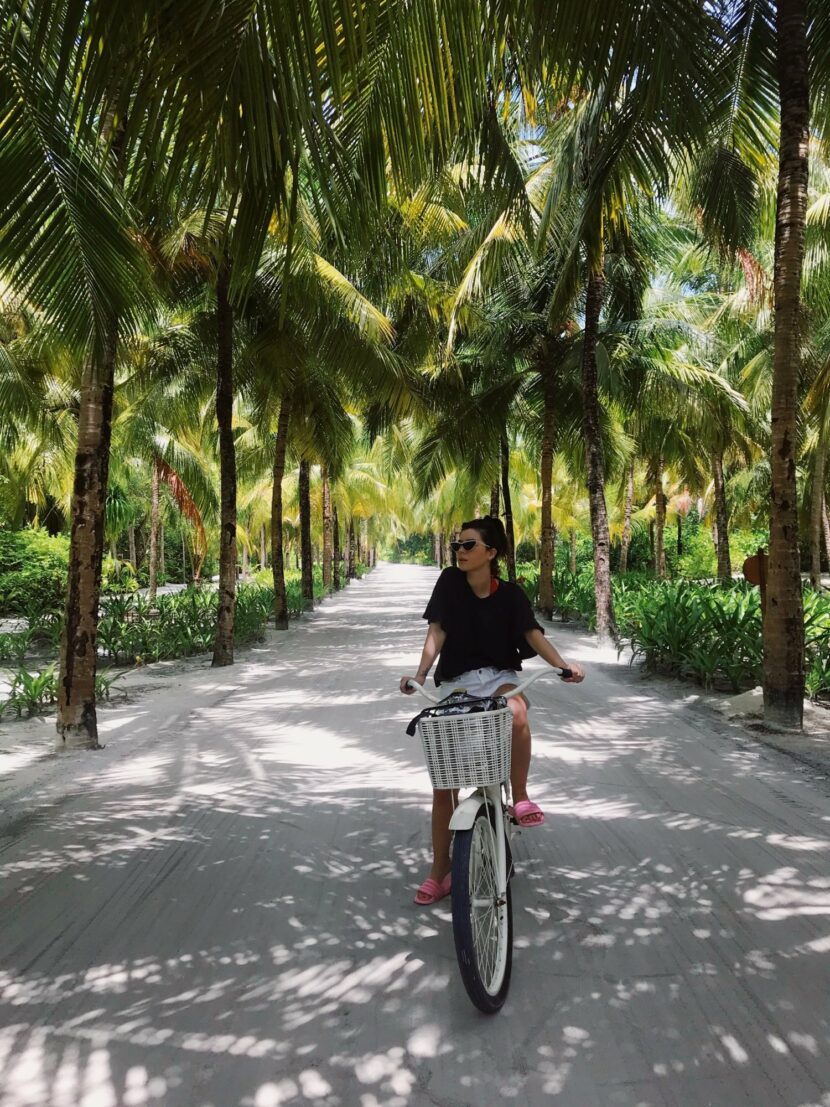 Betty Autier à vélo dans une allée de palmiers au One&Only Reethi Rah