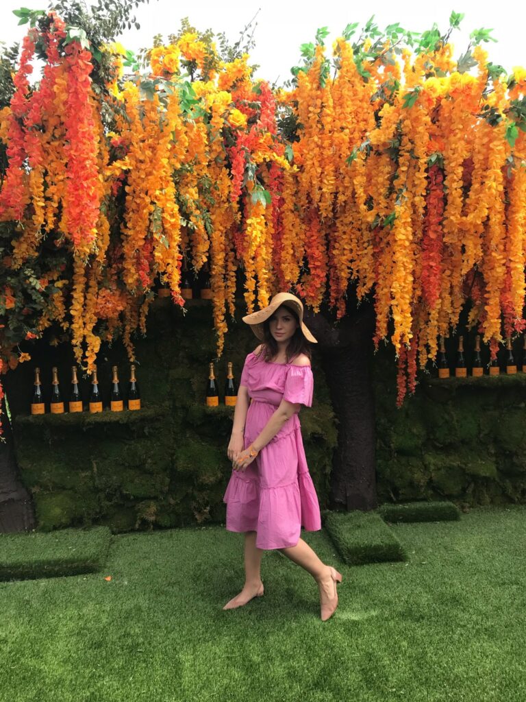 Betty Autier sous l’arbre aux fleurs orange et bouteilles Veuve Clicquot