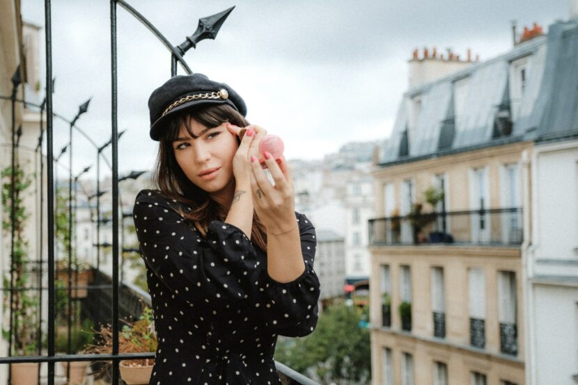 Betty Autier sur un balcon parisien, casquette et robe à pois, pour la collection Bourjois