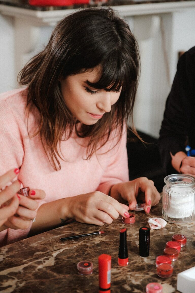Betty Autier en pull rose testant les teintes de sa collection Bourjois