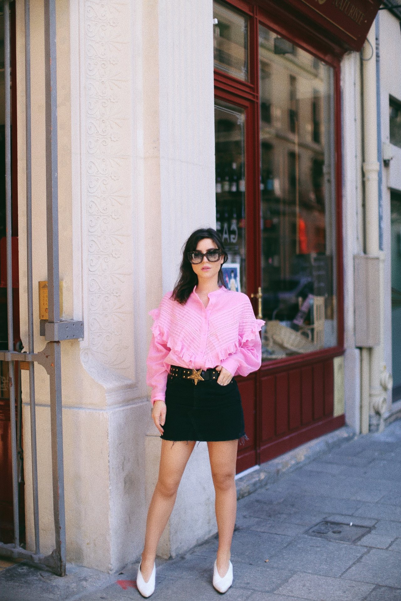 Betty Autier en blouse rose à volants, mini-jupe noire, ceinture étoile et mocassins blancs à Paris