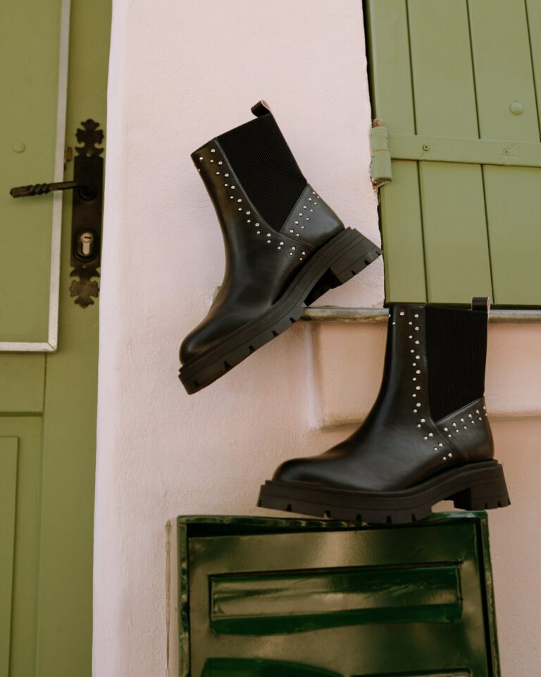 Boots crantées noires cloutées devant des volets verts