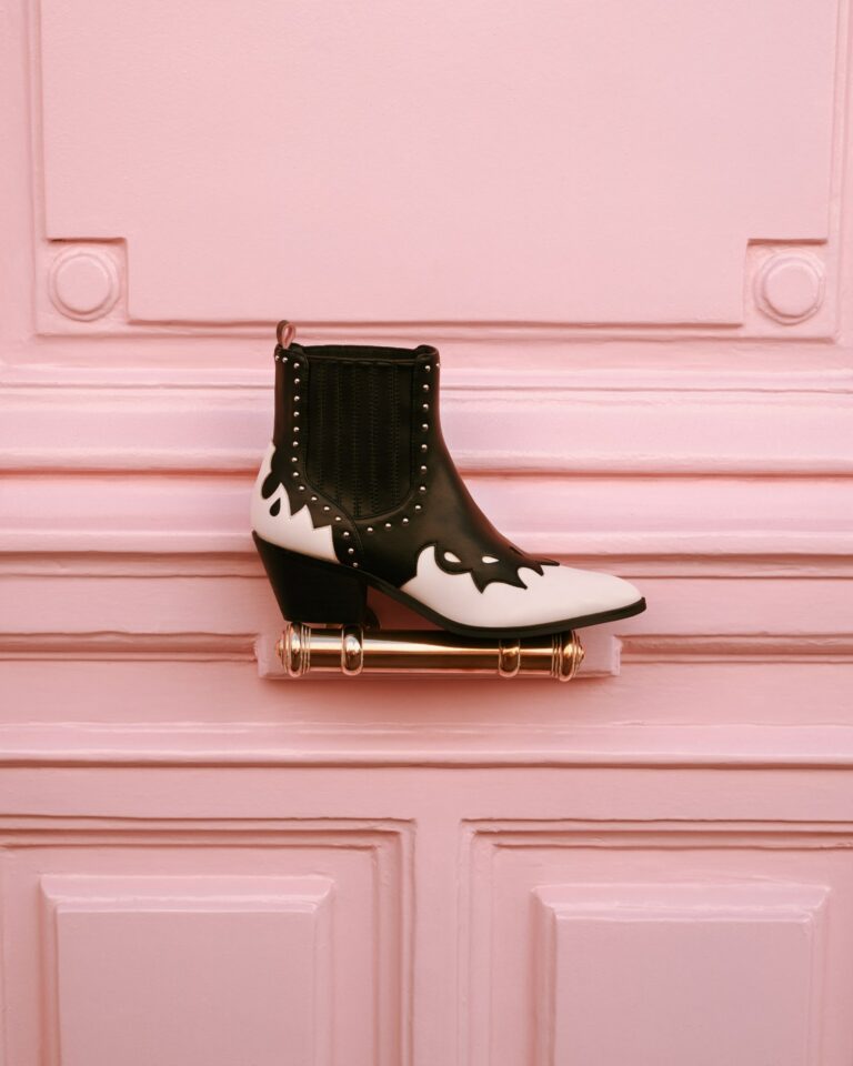 Bottine western noire et blanche posée sur une poignée de porte rose