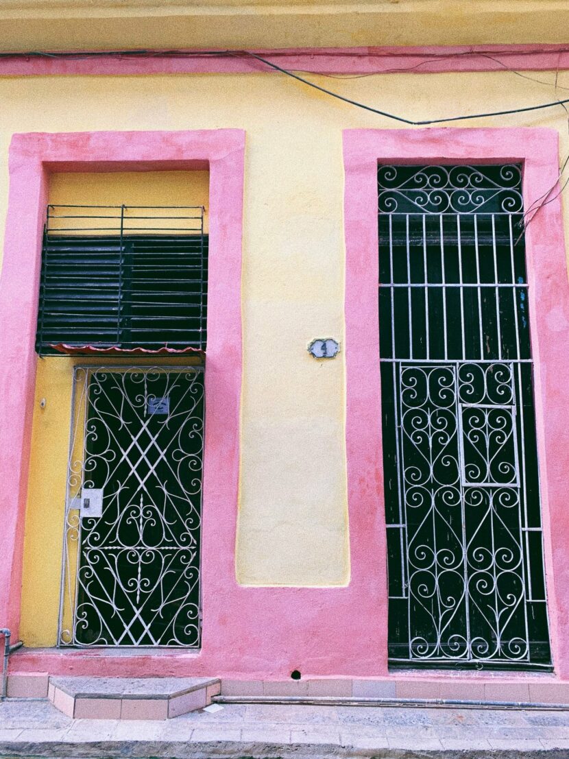 Portes en fer forgé sur une façade rose et jaune à La Havane
