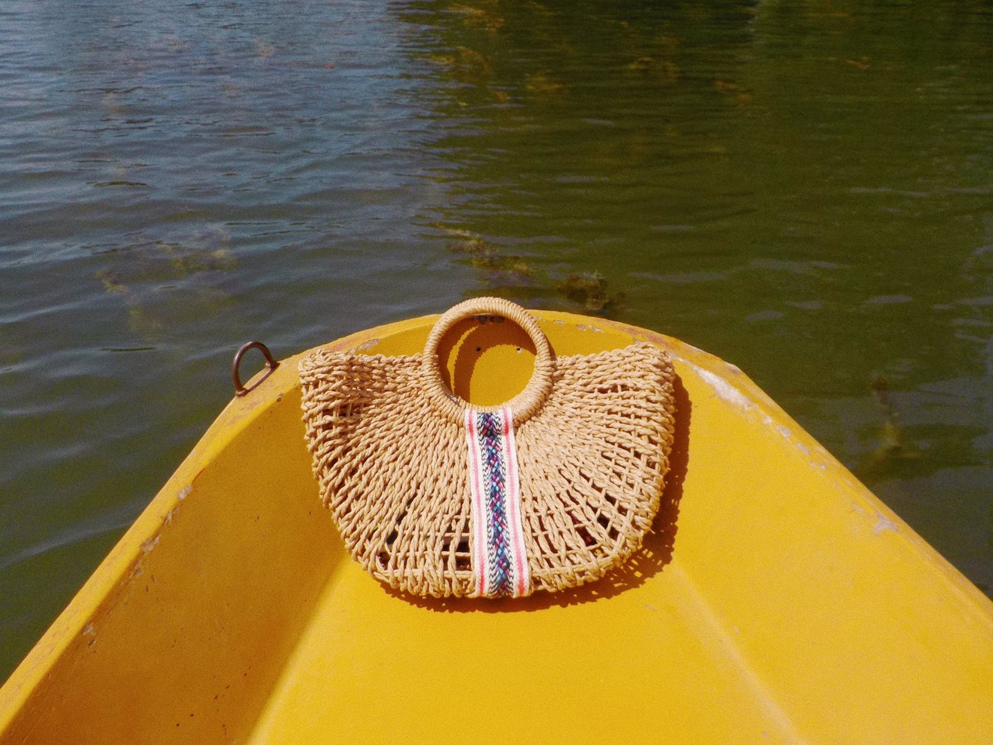 Panier en paille posé à l’avant d’une barque jaune sur le lac