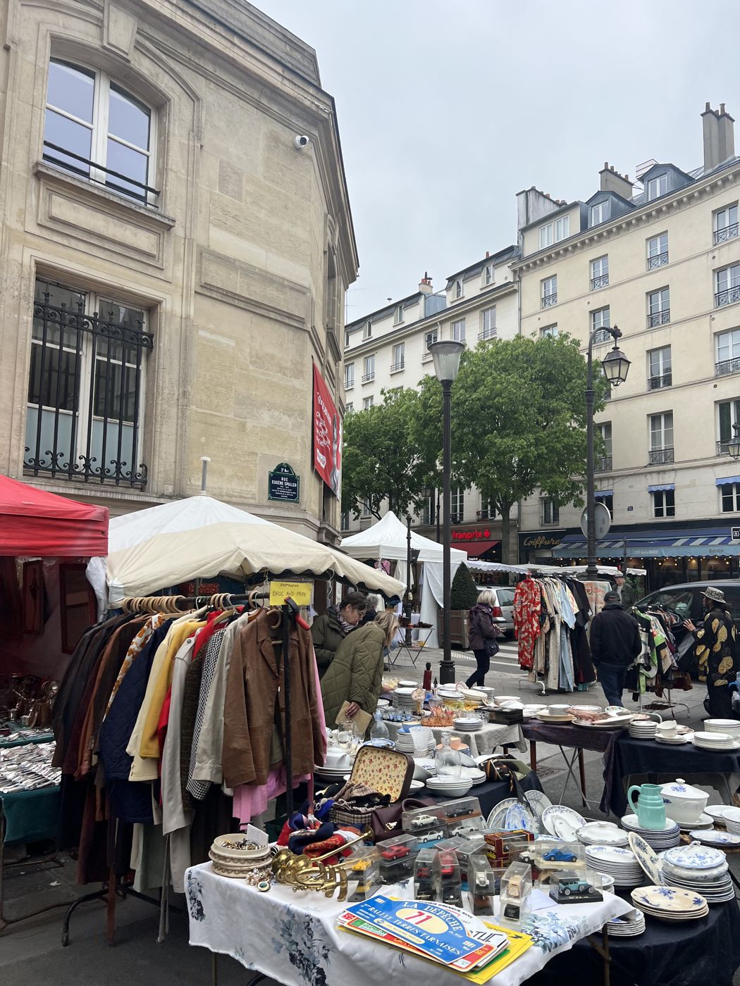 Brocante dans une rue de Paris avec portants de vêtements vintage et vaisselle ancienne