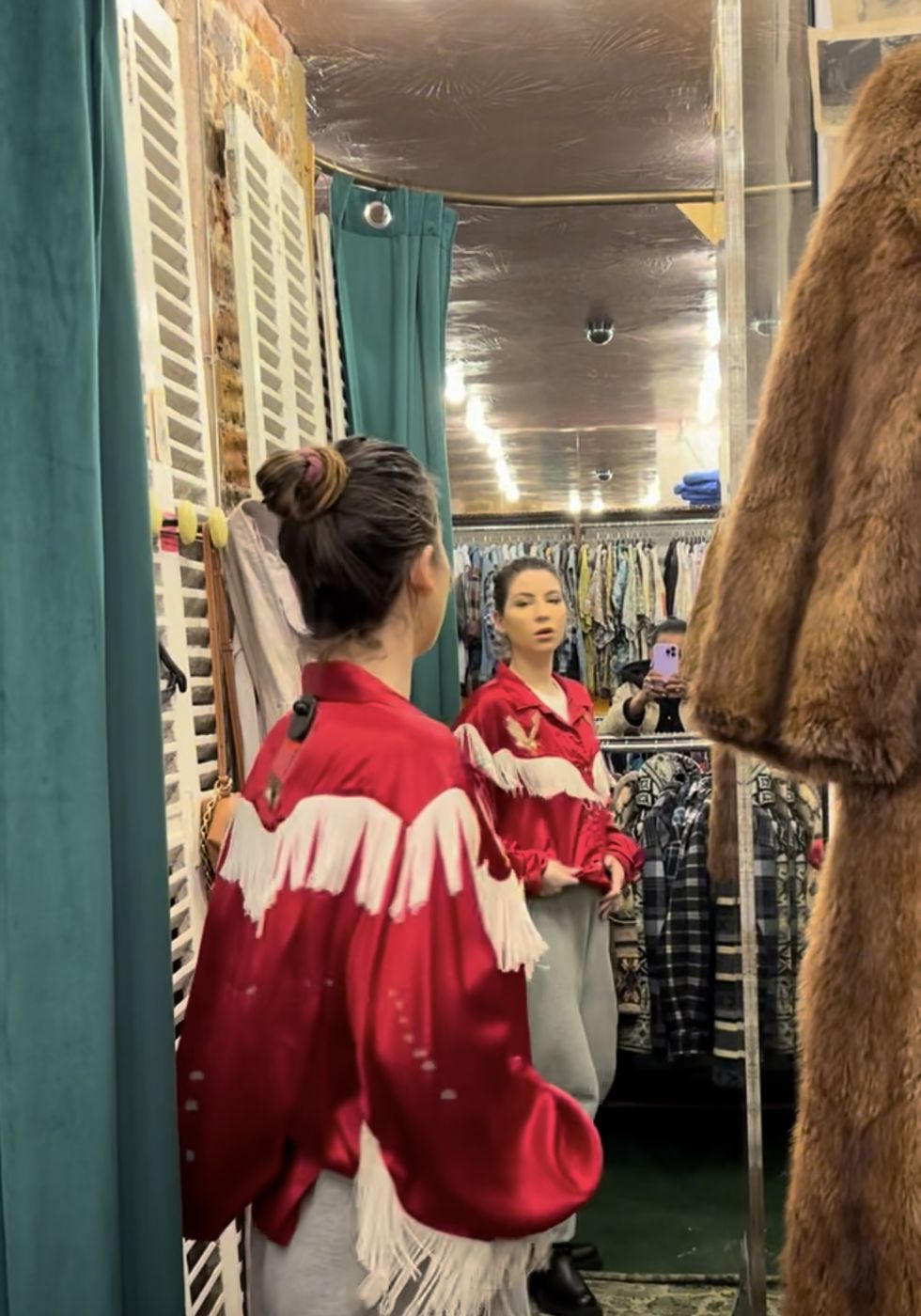 Betty essaie une chemise western rouge à franges en cabine d'essayage