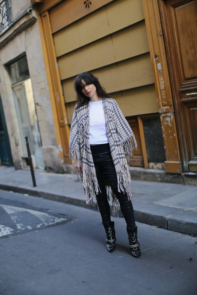 Betty Autier en poncho à franges pied-de-poule et pantalon en cuir dans une rue de Paris