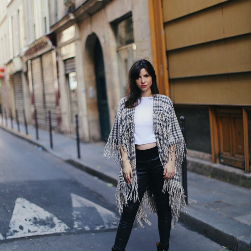 Betty Autier en poncho à franges pied-de-poule, tee-shirt blanc et boots cloutées