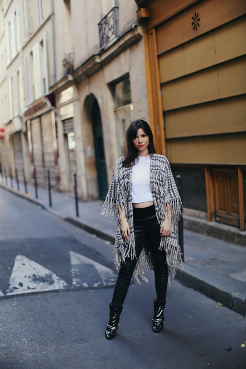 Betty Autier en poncho à franges pied-de-poule, tee-shirt blanc et boots cloutées