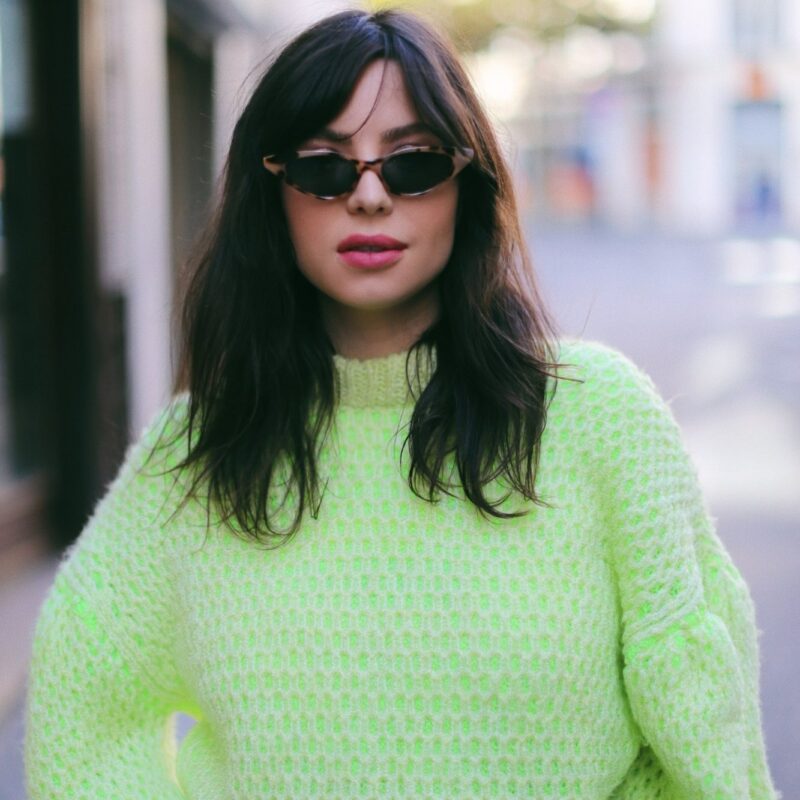 Betty Autier en pull en grosse maille jaune fluo et lunettes de soleil