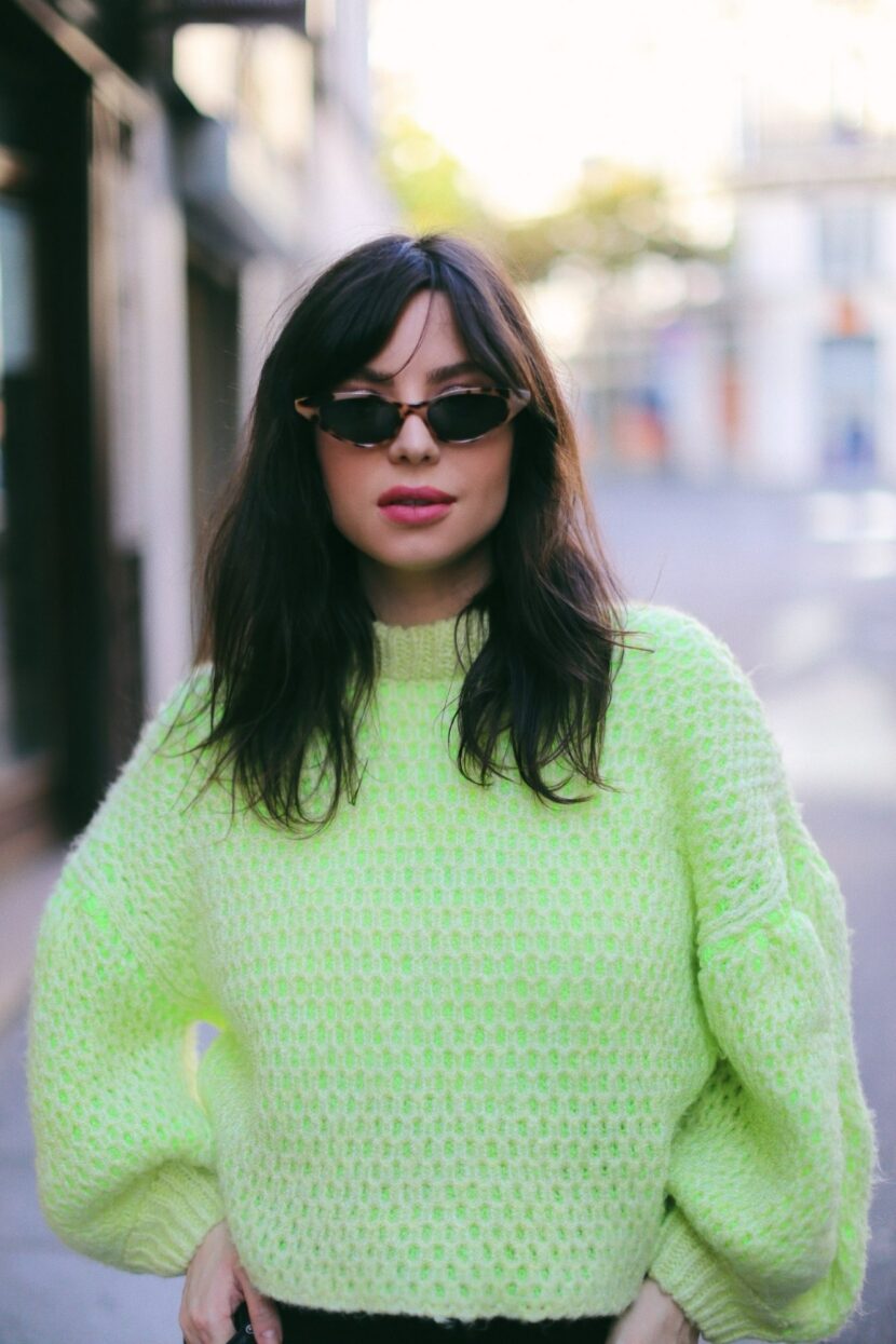 Betty Autier en pull en grosse maille jaune fluo et lunettes de soleil