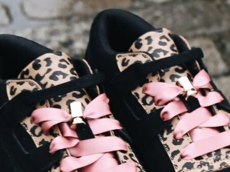 Zoom sur le bijou doré et les lacets en satin rose des Reebok Workout Ripple x Betty Autier